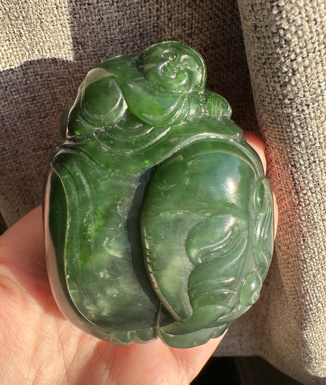 Green jade carving of a young boy riding an elephant seen from another angle.
