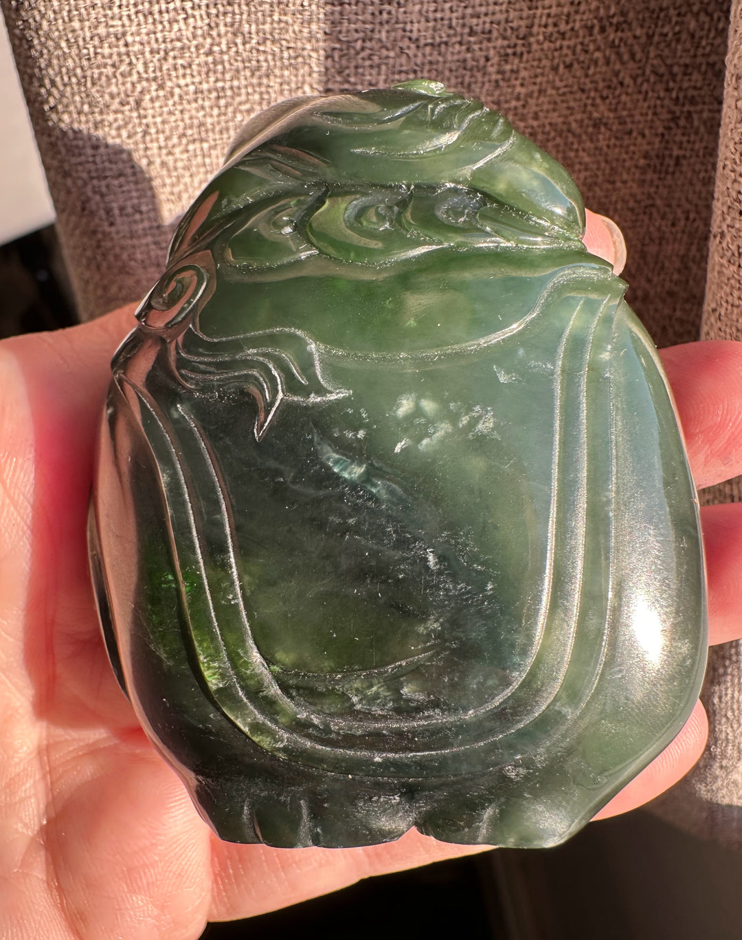 Green jade carving of a young boy riding an elephant close up showing top and side details.
