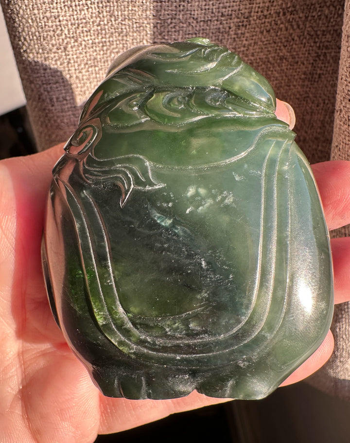 Green jade carving of a young boy riding an elephant close up showing top and side details.