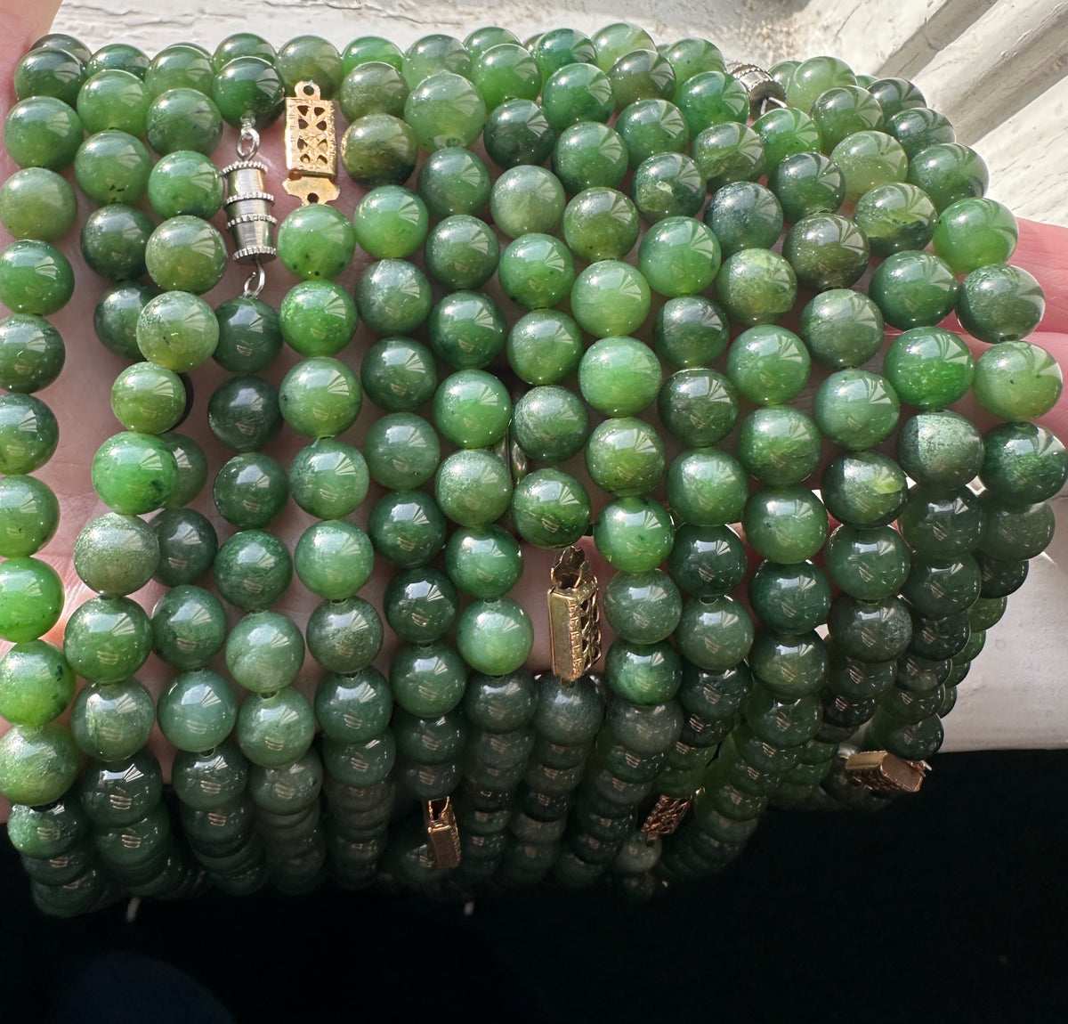 Close up of a green nephrite jade bead strand with 8mm beads awaiting restringing
