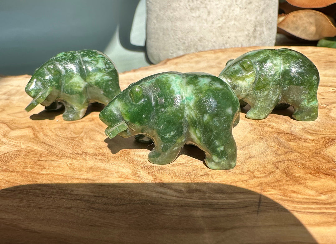 Three jade bear figurines arranged on a wooden table.