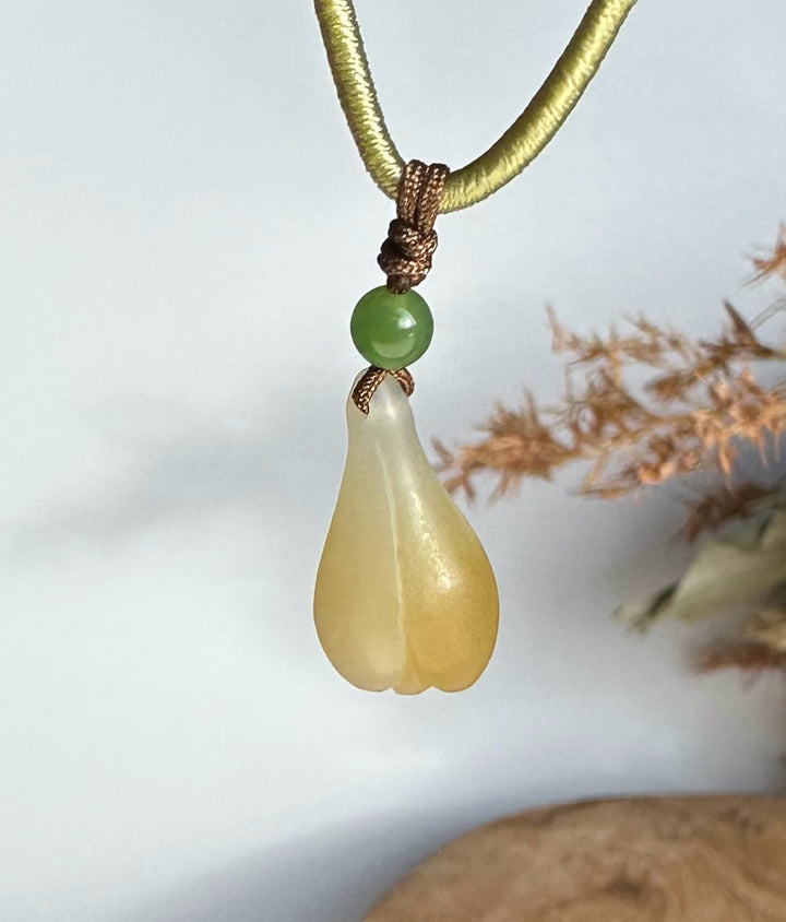Teardrop honey white nephrite jade pendant with a green bead on an olive green cord