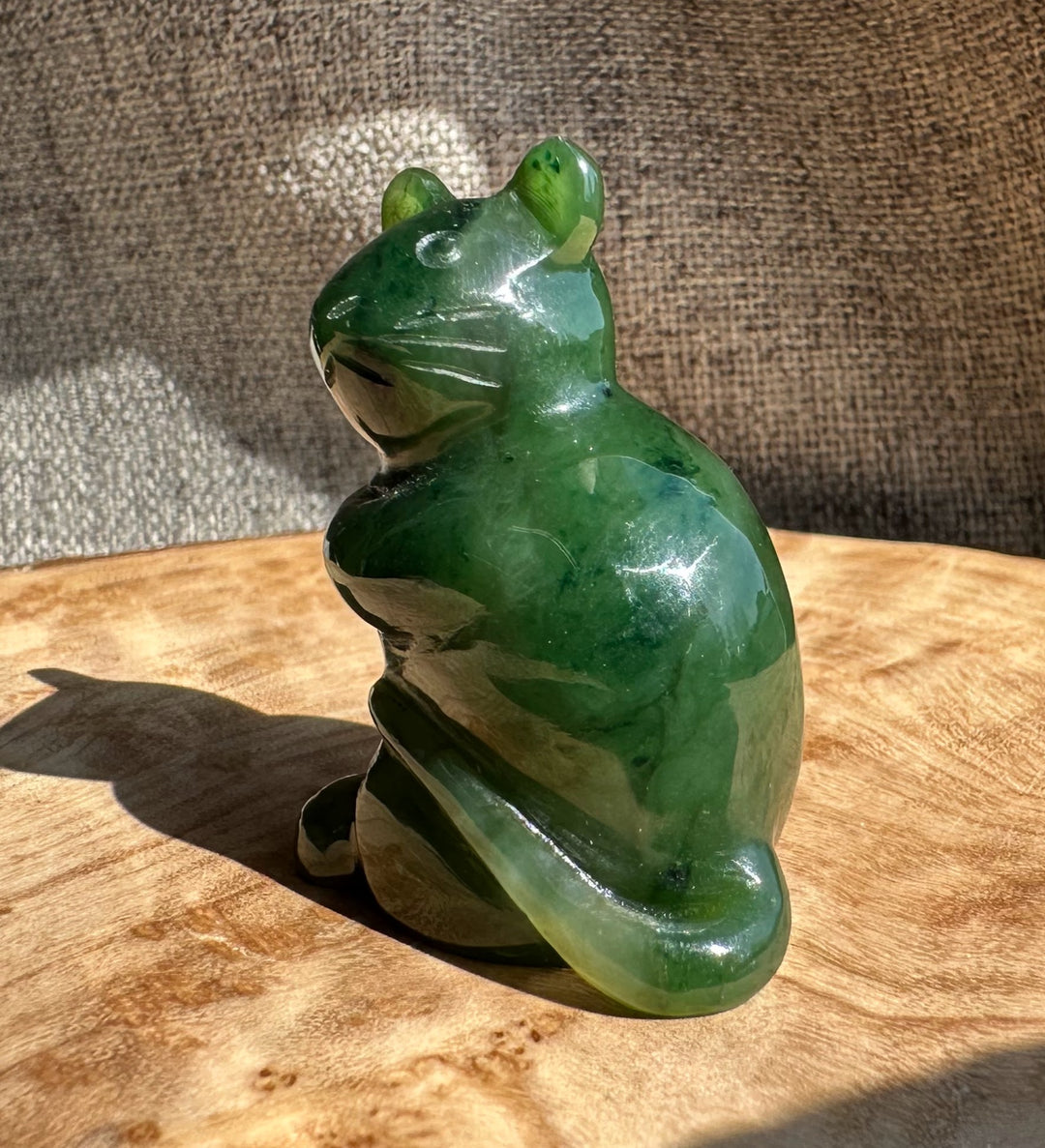 Three-quarter view of a green jade mouse figurine on a wooden surface.