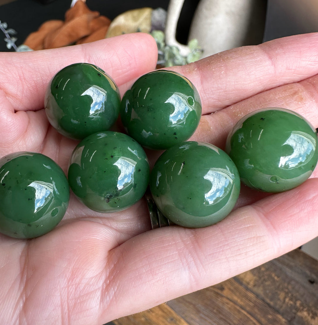 Handful of 20mm jade beads with drilled holes held in a palm