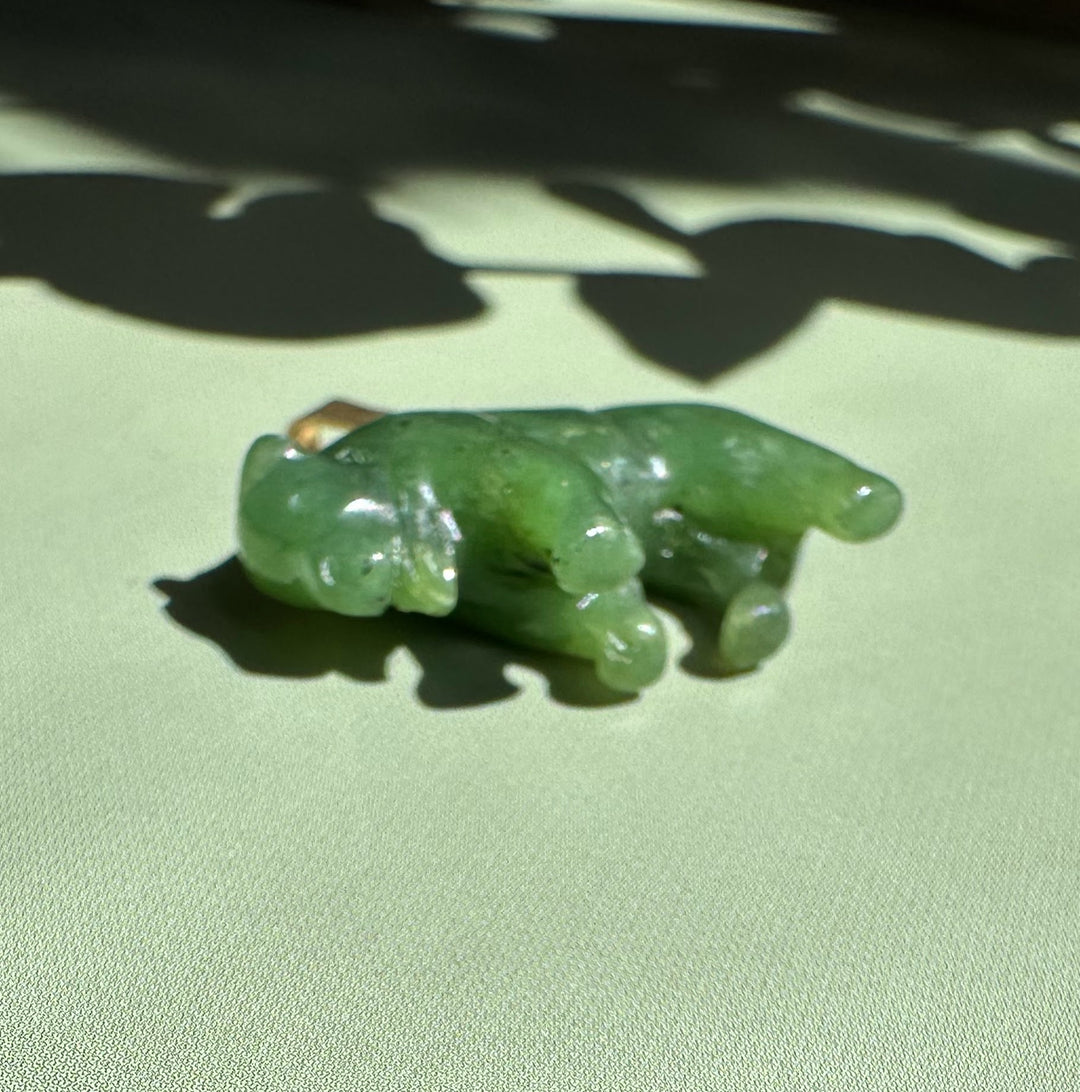 Canadian Jade Bison Charm 21mm in green jade with a small gold bail on a pale surface