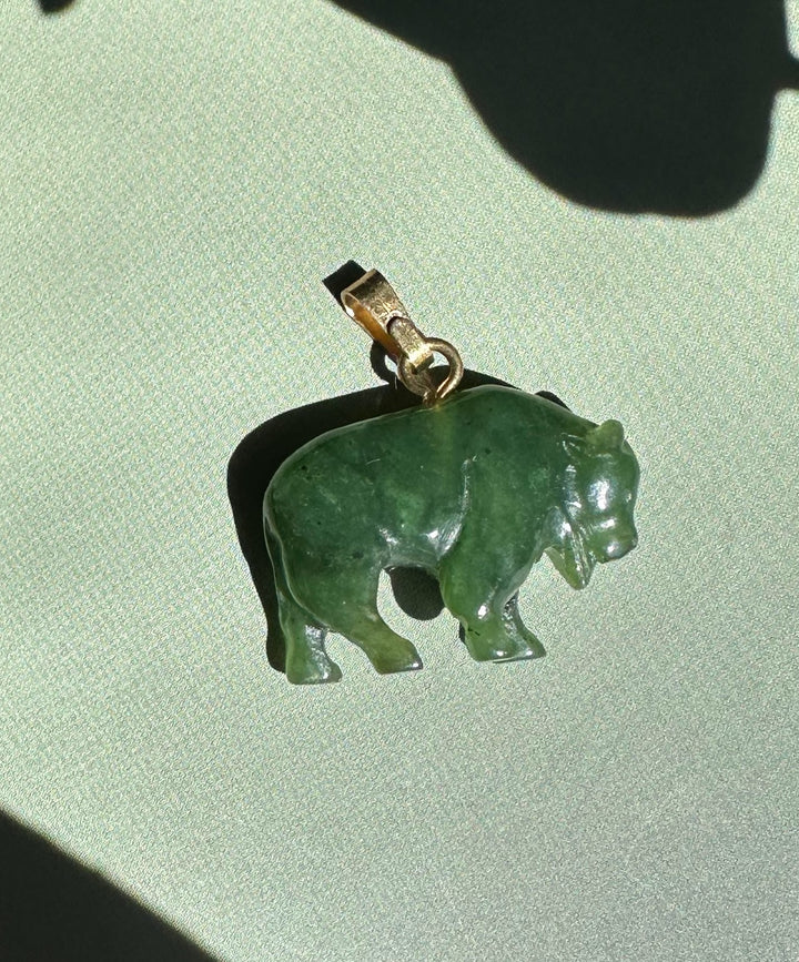 Canadian Jade Bison Charm pendant in green jade with a metal bail on a light background