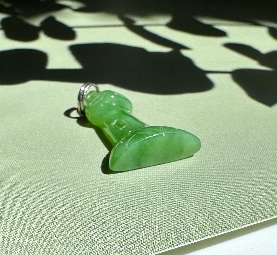 Side view of the green jade lighthouse charm with loop against a sunlit background