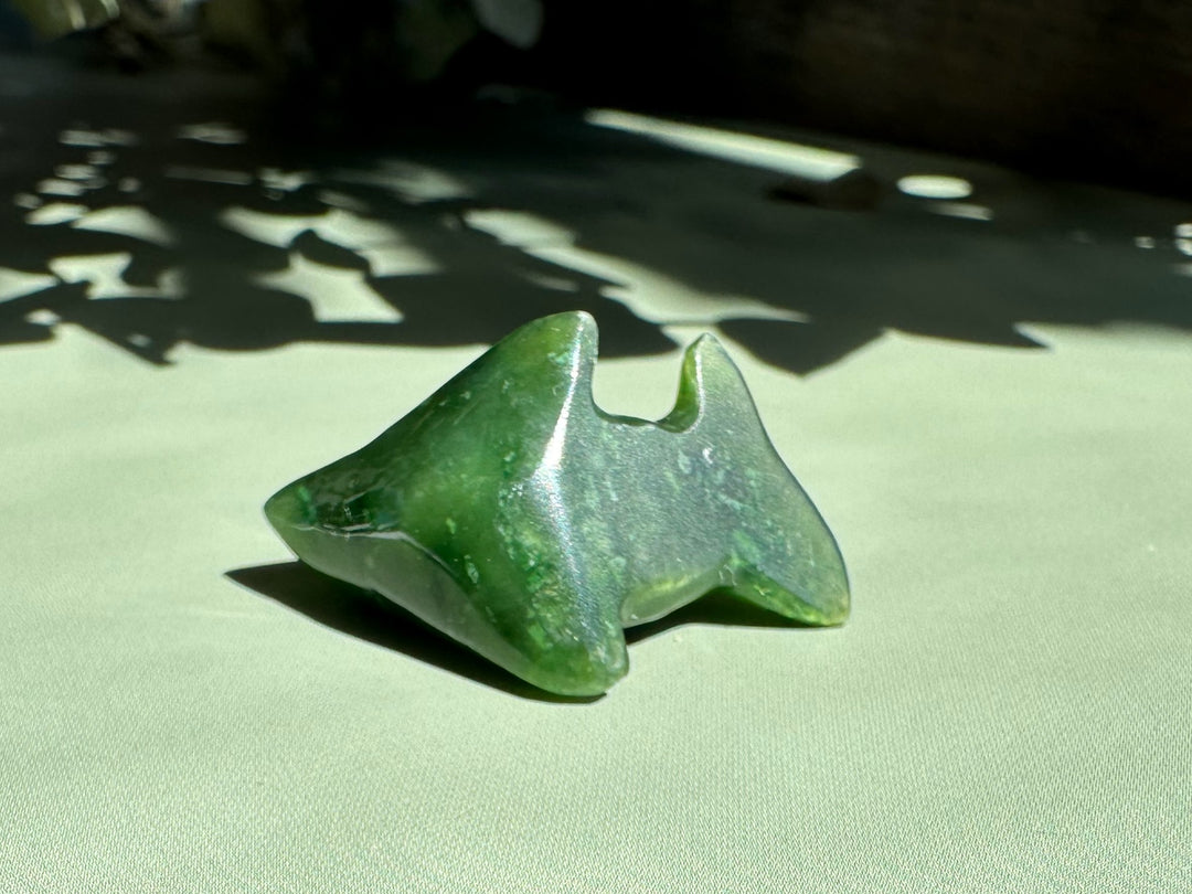 Close up of green jade seal charm with a silver bail on a light green background