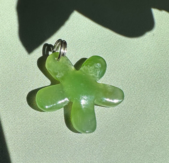 Close-up of a 16mm pale green jade flower charm with a silver jump ring