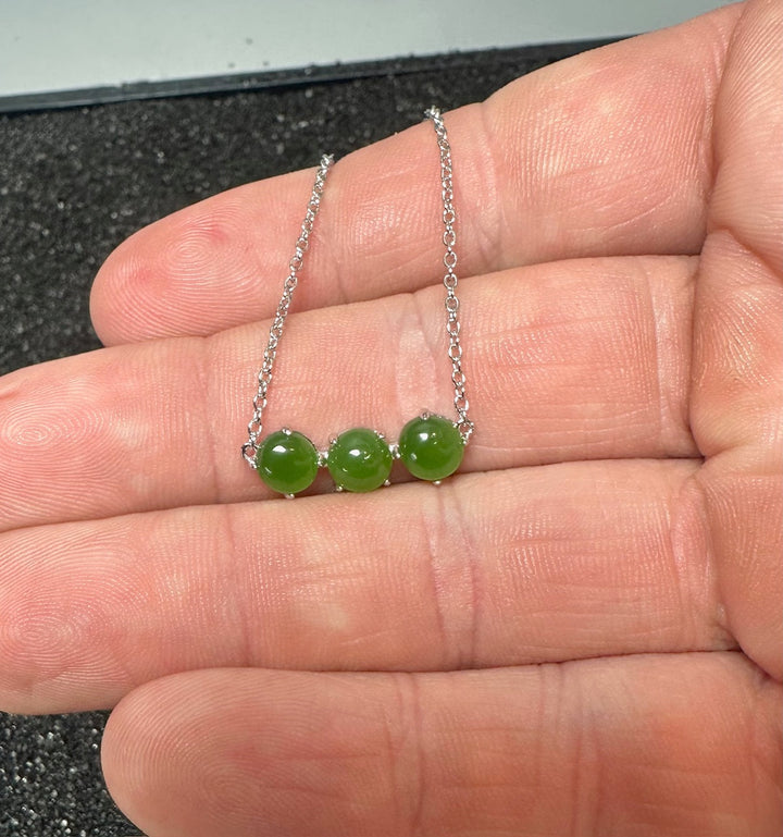 Canadian Jade and Silver three bead necklace with green jade stones on a silver chain held in the hand
