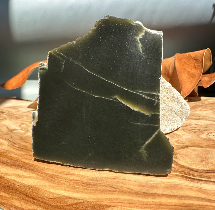 Wyoming Honey Olive Jade slab with dark olive surface and lighter outer edge on a wooden table
