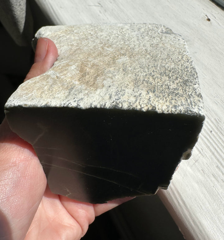 Triangular Wyoming Honey Olive Jade piece with a black interior and beige rind
