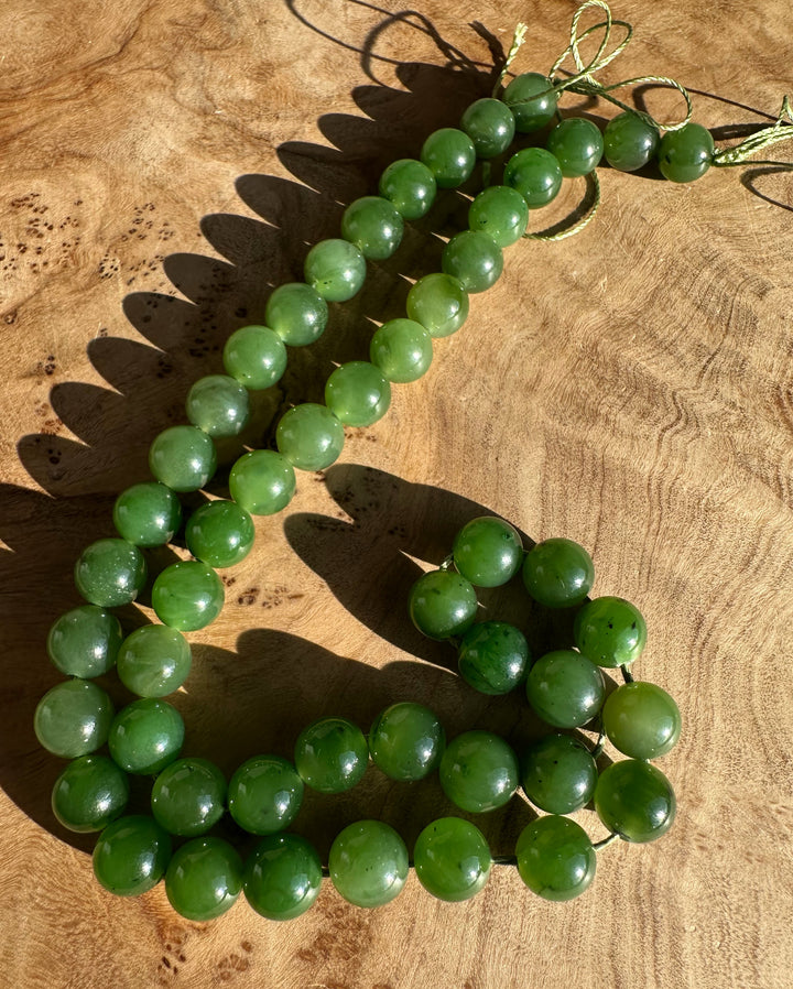 Green 8mm Canadian beads on a string laid on wood in a curved strand