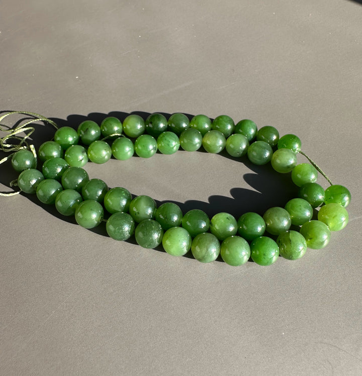 Close up of green 8mm unstrung Canadian beads in a circular loop on a gray background