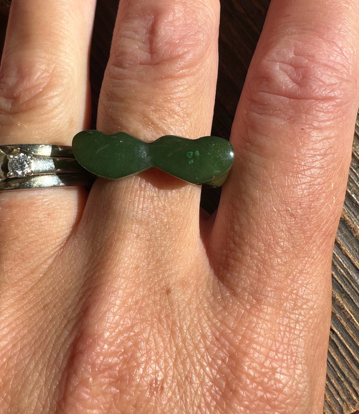 Person wearing the green jade hearts band ring on the finger, highlighting the curved heart design.