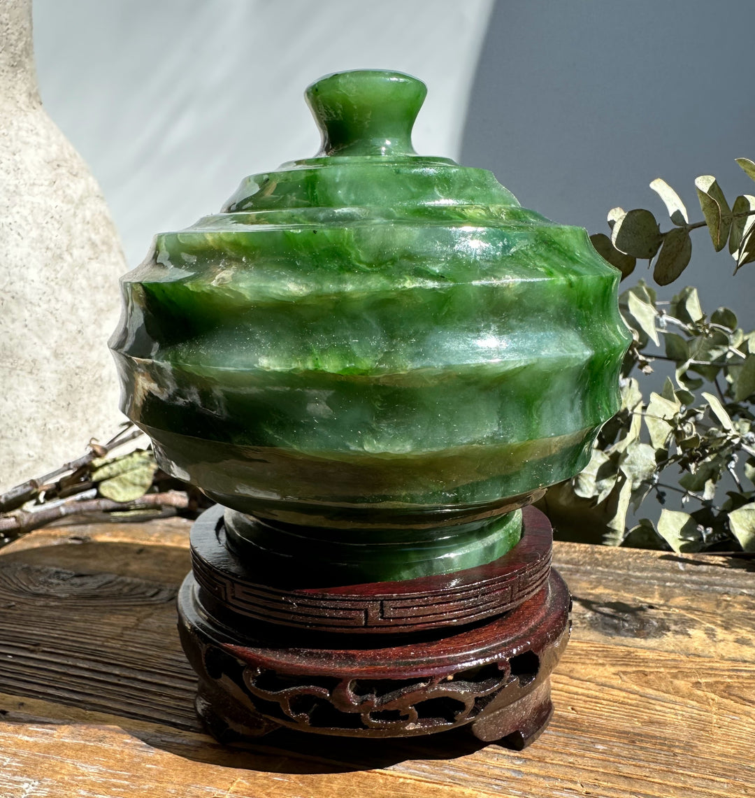 Polar Jade Pot with lid on a carved wooden stand in sunlight