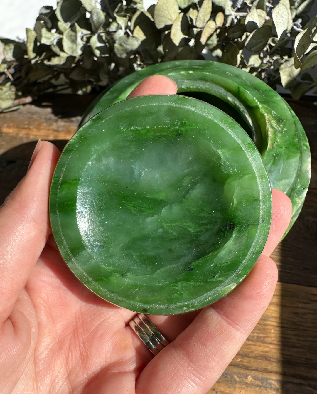 Hand holding the Polar Jade Pot lid from above, exposing the circular green jade with subtle veining.