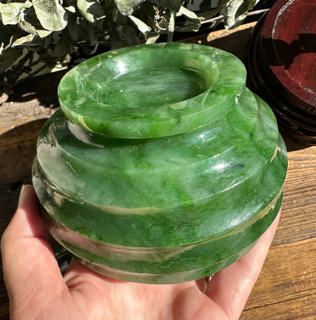 Close up of a glossy Polar Jade Pot 4.2 inch held in a hand, showing its rounded, stacked form.