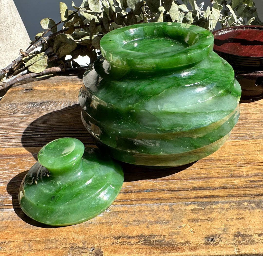 Two green Polar Jade Pots of different sizes with lids, set on a weathered wooden surface outdoors.