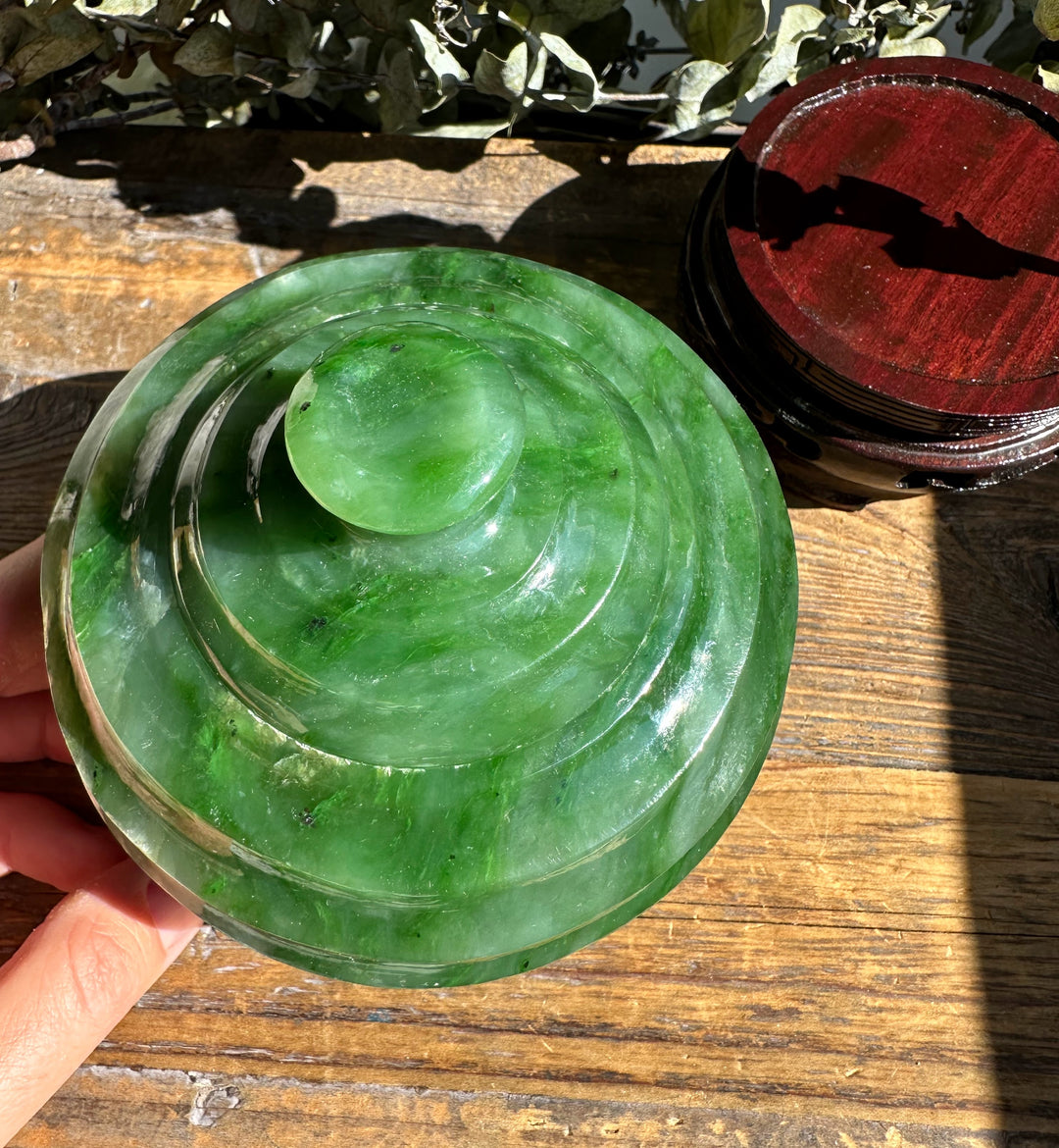 Polar Jade Pot lid with a round knob, held over a weathered wooden surface