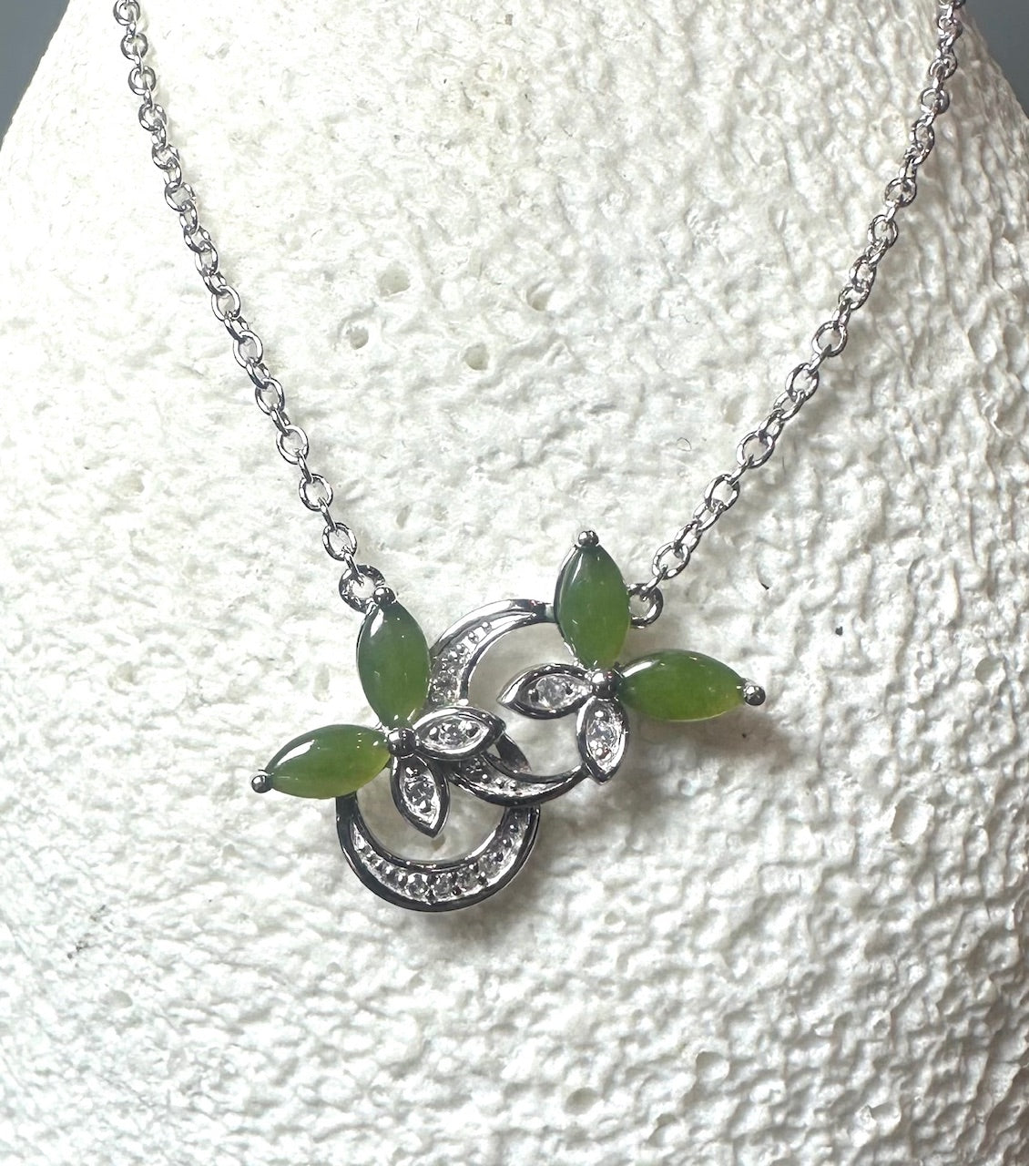 Silver butterfly pendant with green marquise stones and crystal accents on a silver chain.