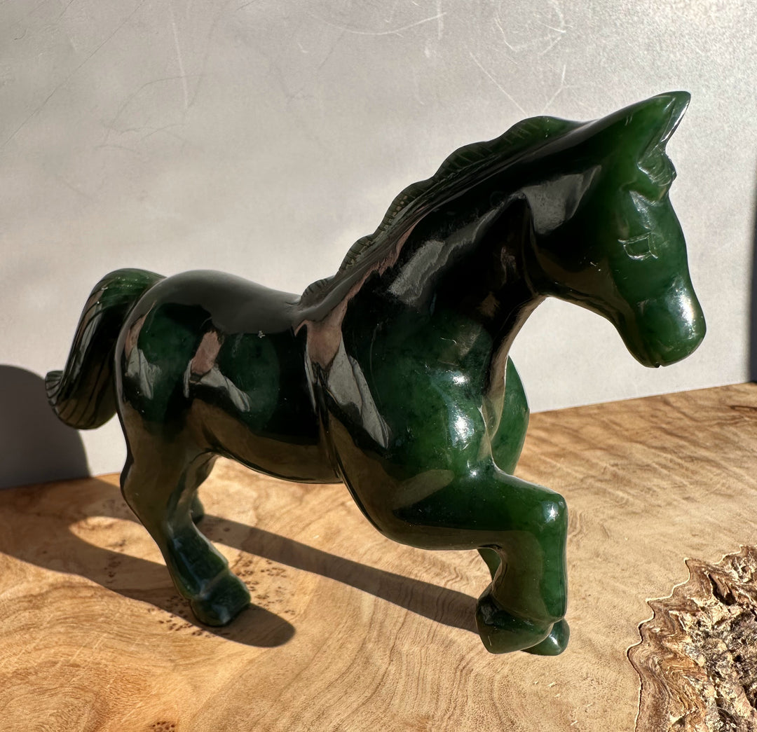 Three-quarter view of a glossy dark green nephrite jade horse sculpture five inches long.