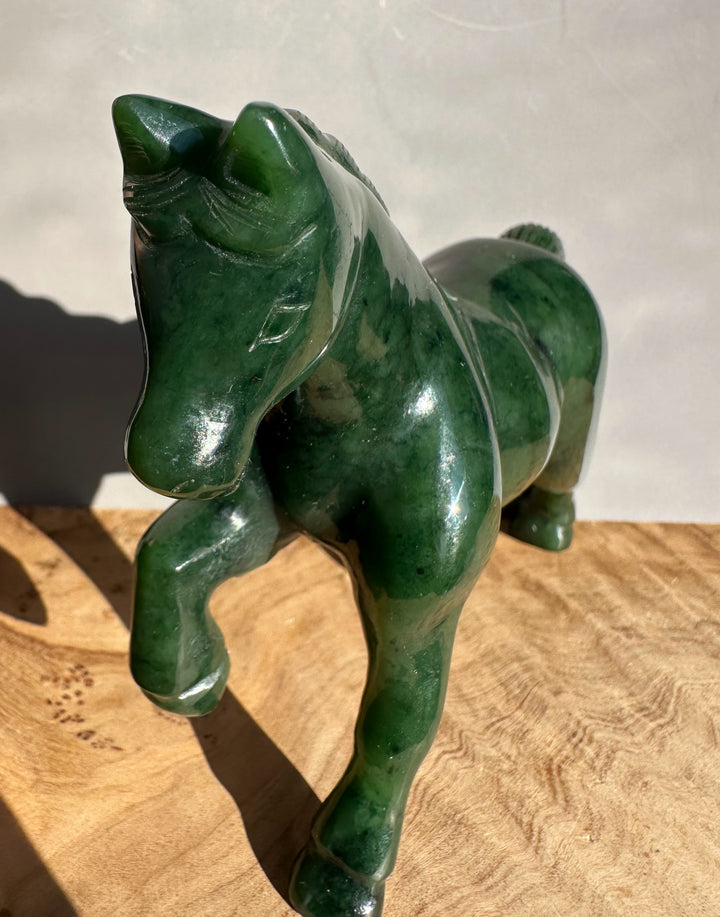 Green nephrite jade horse figure captured from a high angle showing a glossy body and curved tail