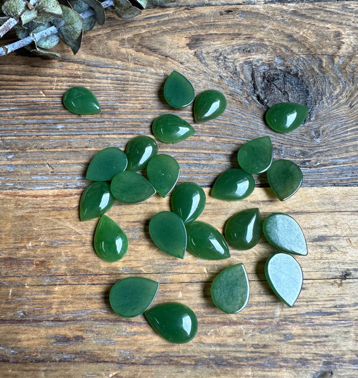 Group of glossy green pear teardrop cabochons on wood with visible backs