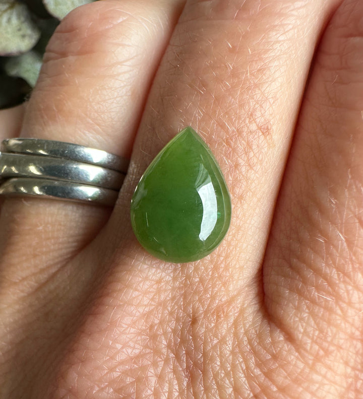Green pear teardrop cabochon mounted on a ring worn on the finger