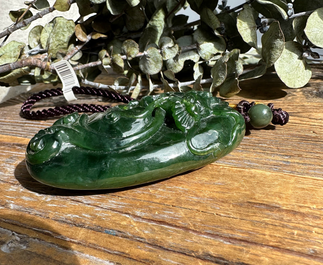 Green jade dragon pocket pendant with a detailed carved body on a purple braided cord