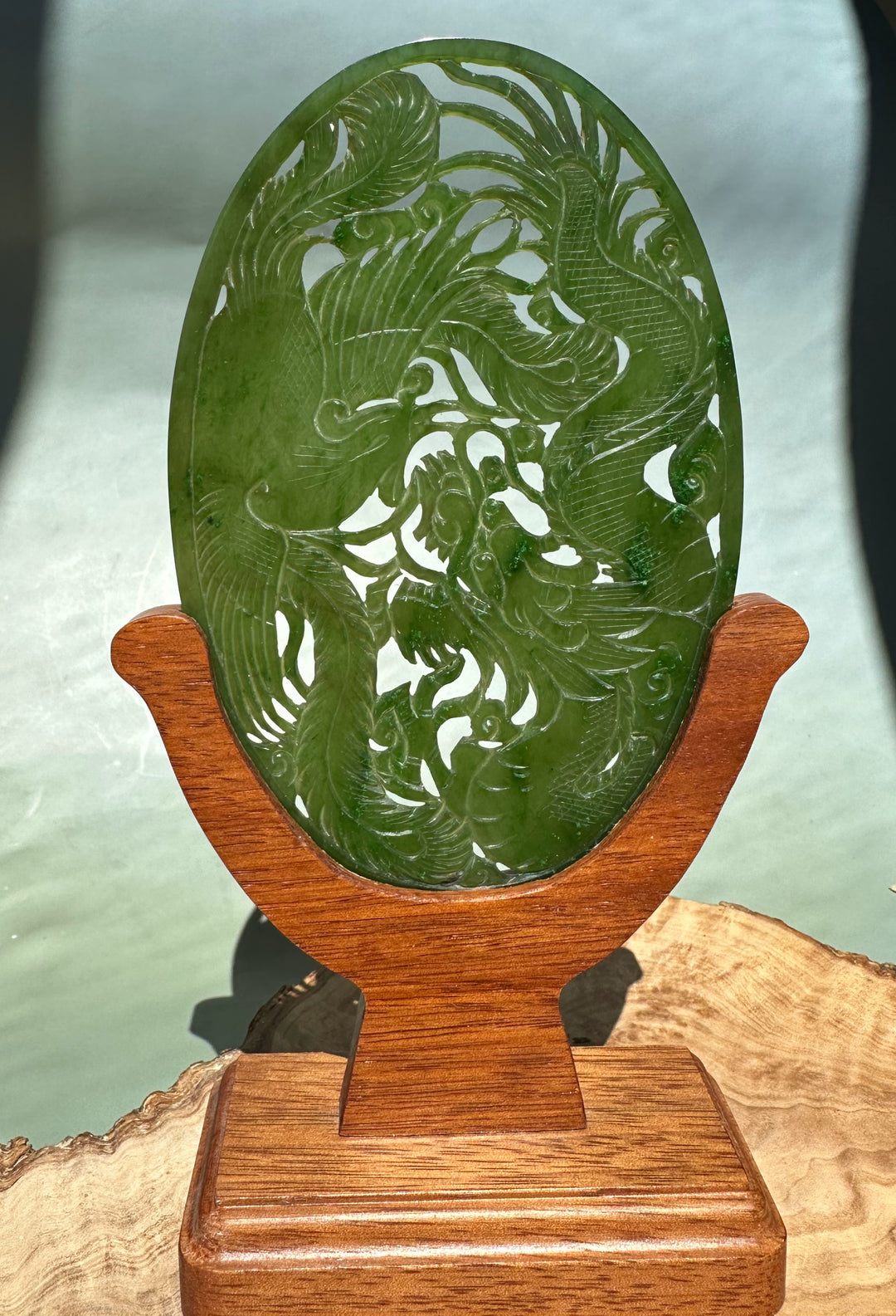 Canadian Jade Dragon and Phoenix Screen oval in green jade displayed on a wooden stand