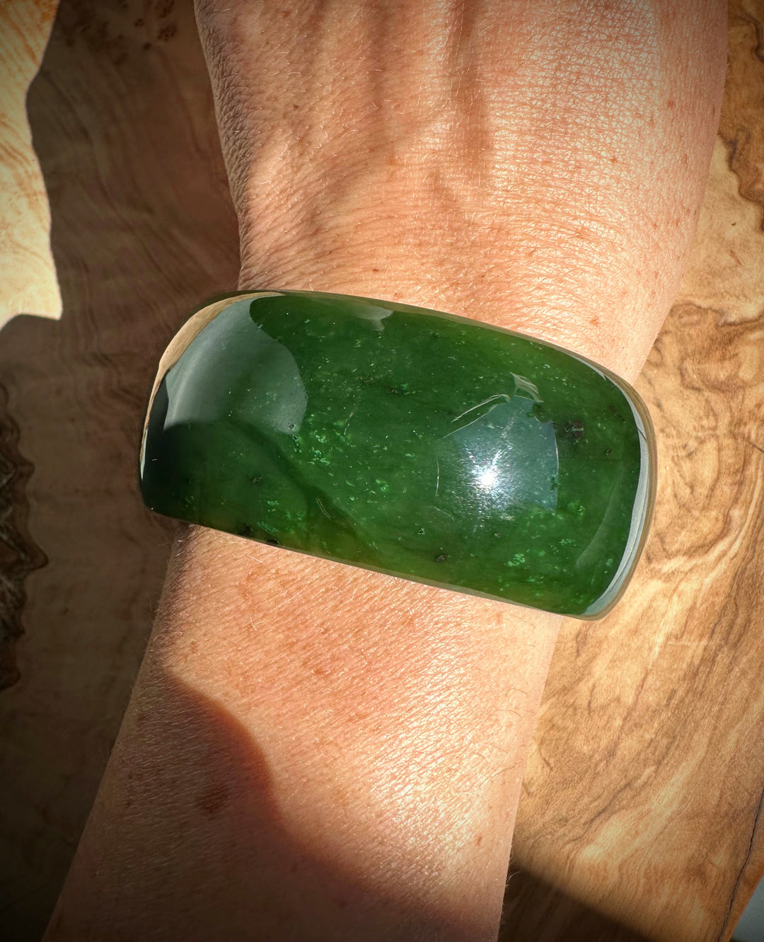 Wrist with the wide green Jade Bangle, a thick polished bracelet