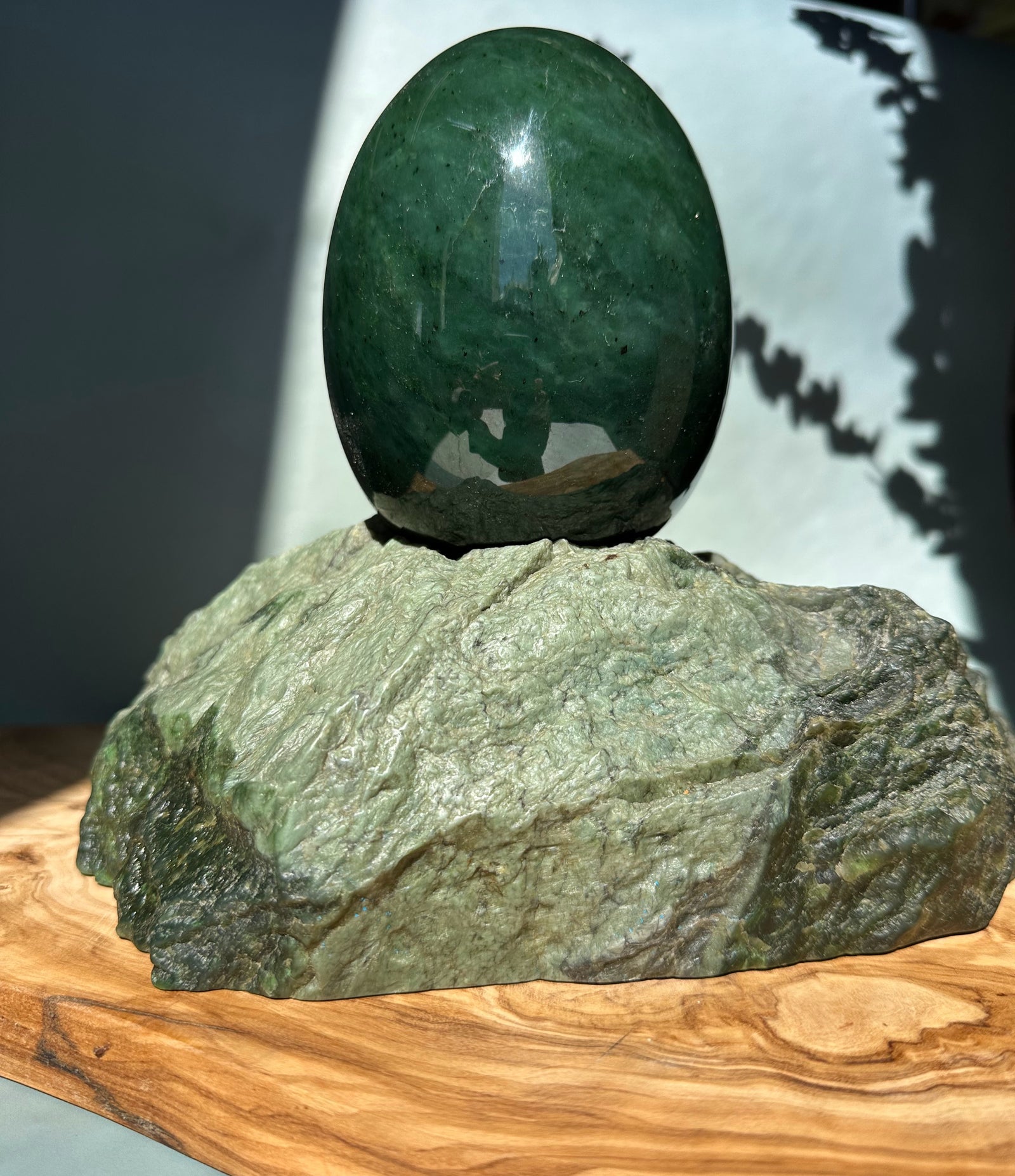 Dark green jade egg perched on a rough textured rock base