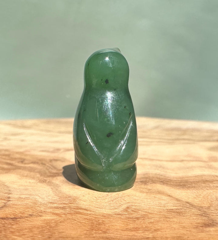 Small Canadian jade penguin figurine about 1 inch tall on a wooden surface