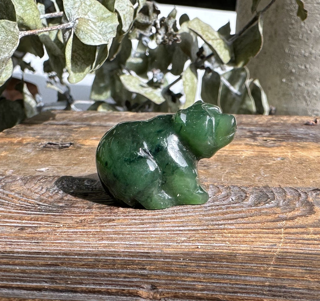 Sitting Canadian jade bear carved from green jade on a wooden surface
