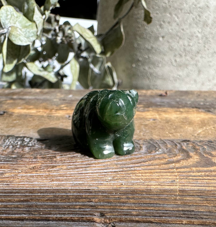 Three-quarter view of a green jade sitting bear on a wooden surface