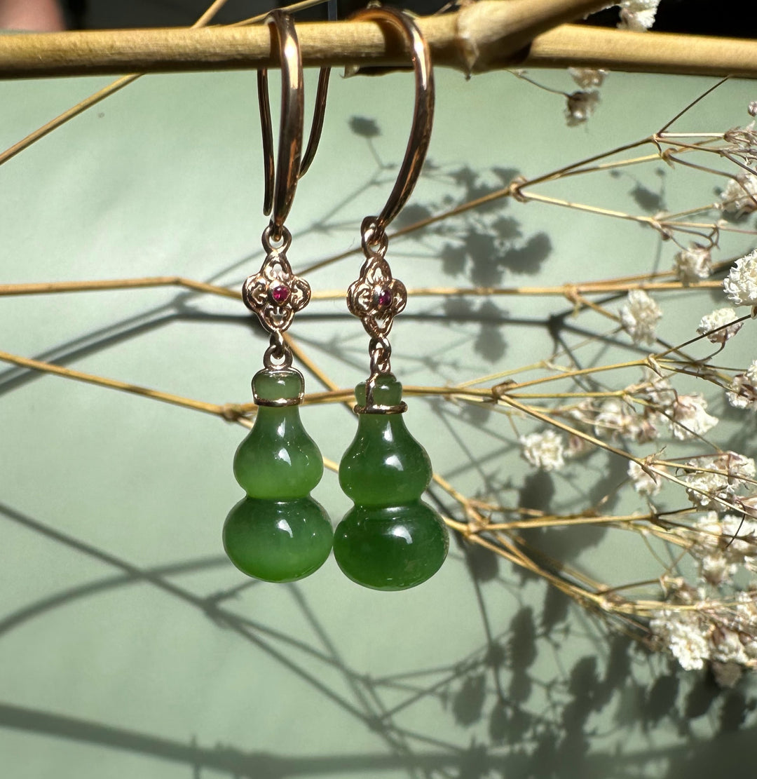 Dangling earrings with rose gold hooks, ornate filigree top with a pink gemstone and green jade gourd pendants.