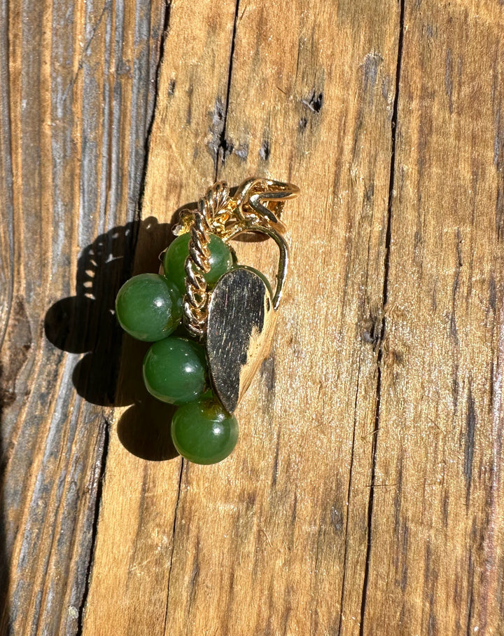 Side view of Vintage Jade Grape Pendant on wood, gold leaf bail and coiled wire