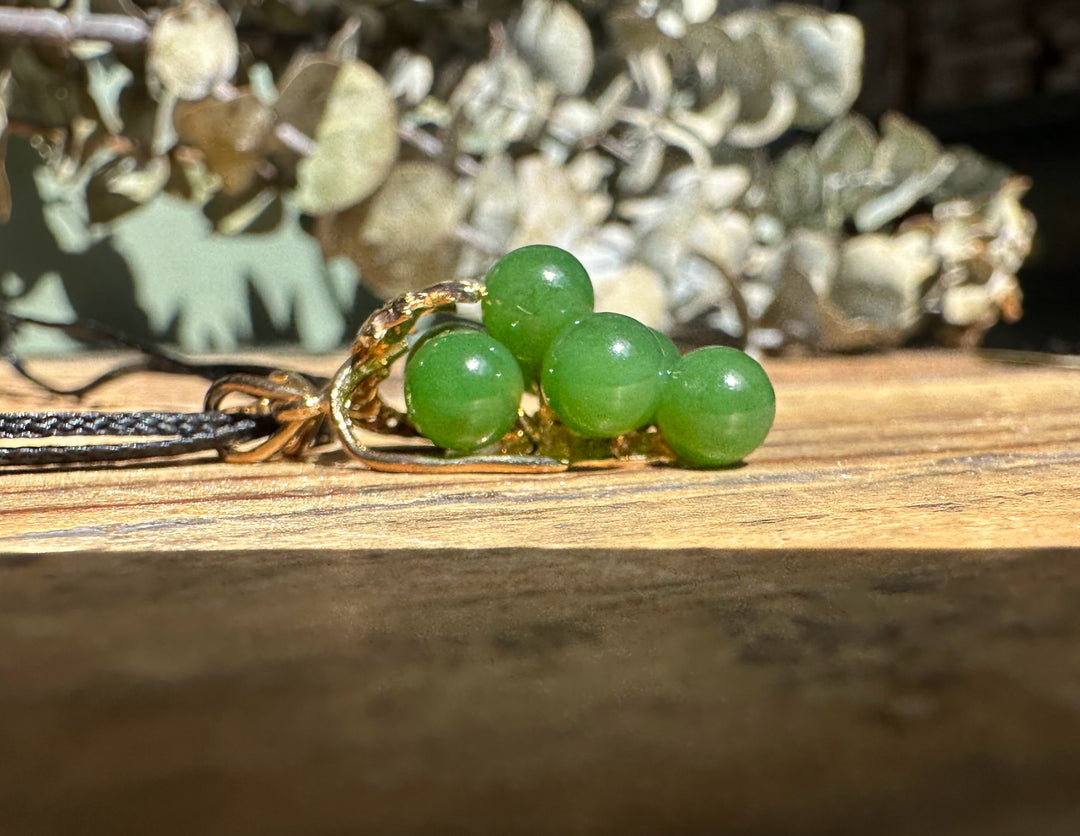 Close up of Vintage Jade Grape Pendant showing four green jade beads and gold wire wrapping