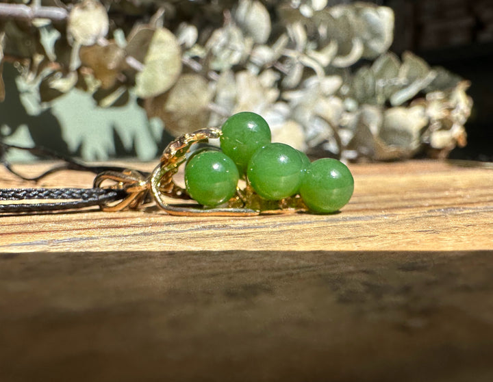 Close up of Vintage Jade Grape Pendant showing four green jade beads and gold wire wrapping