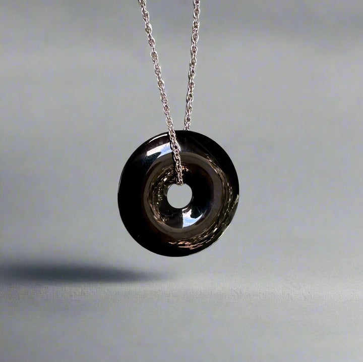 Dark Australian Jade donut pendant suspended on a silver chain.