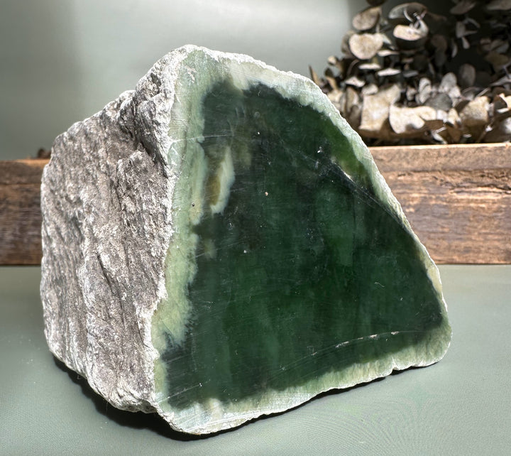 Block of Siberian nephrite rough revealing a green face and rugged gray exterior.