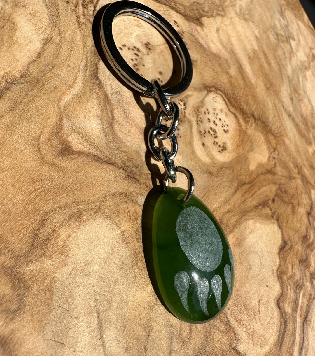 Angled view of green teardrop keychain showing the bear paw design and metal ring at the top