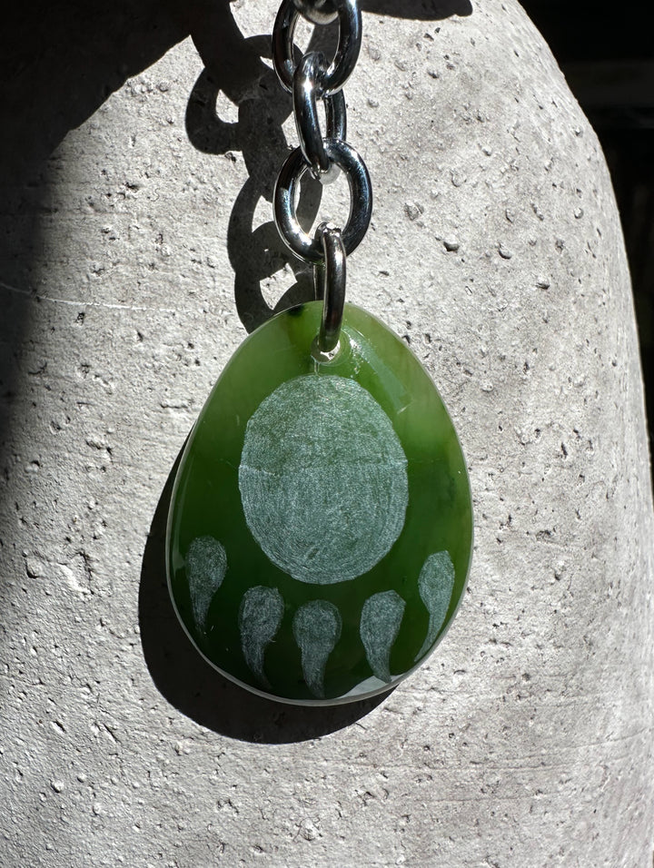 Green circular keychain charm with paw print pattern on a silver chain