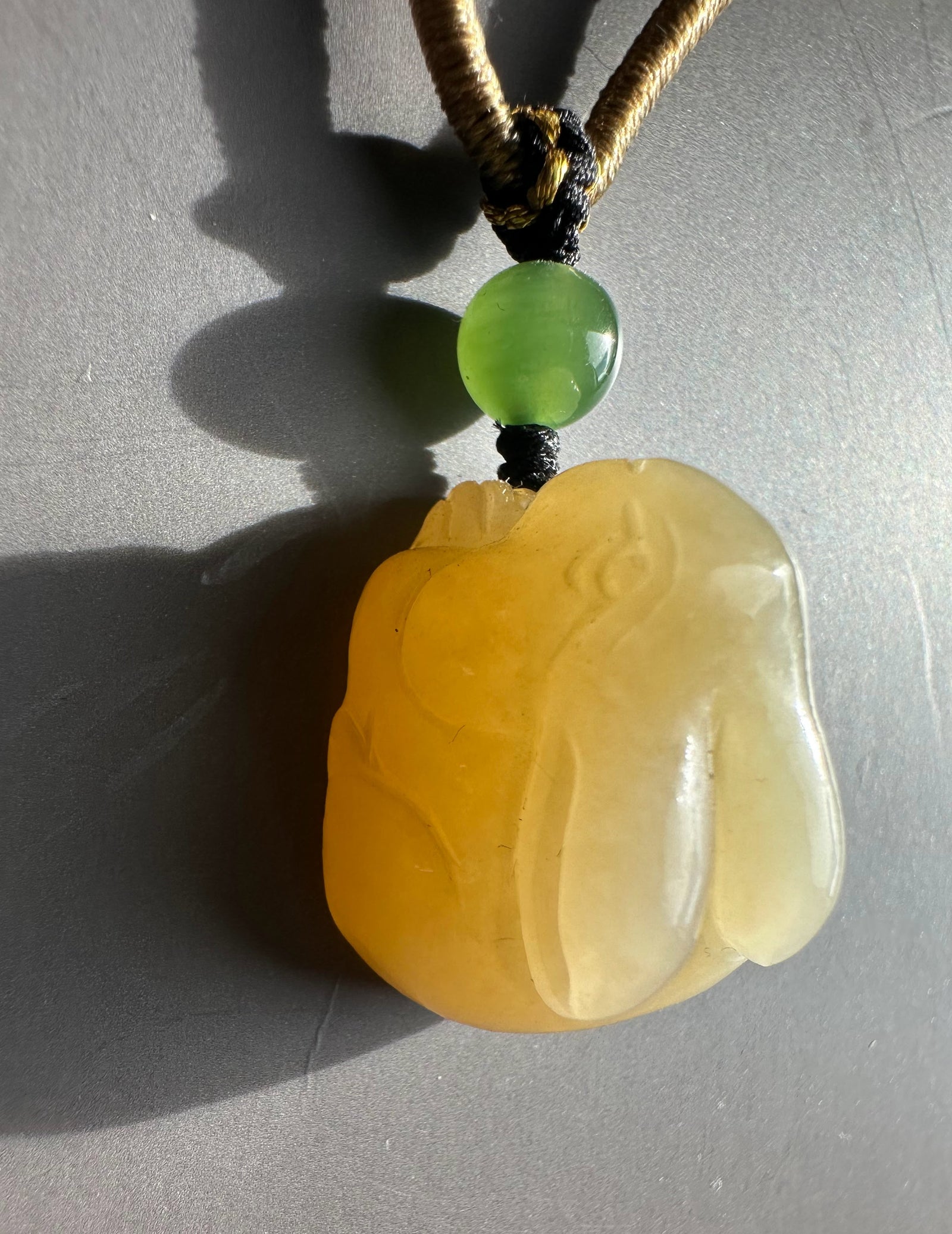 Honey nephrite jade bunny pendant with a green bead above on a braided cord