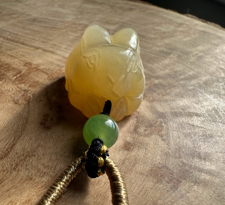 Honey nephrite jade bunny pendant with a round green jade bead on a knotted black cord