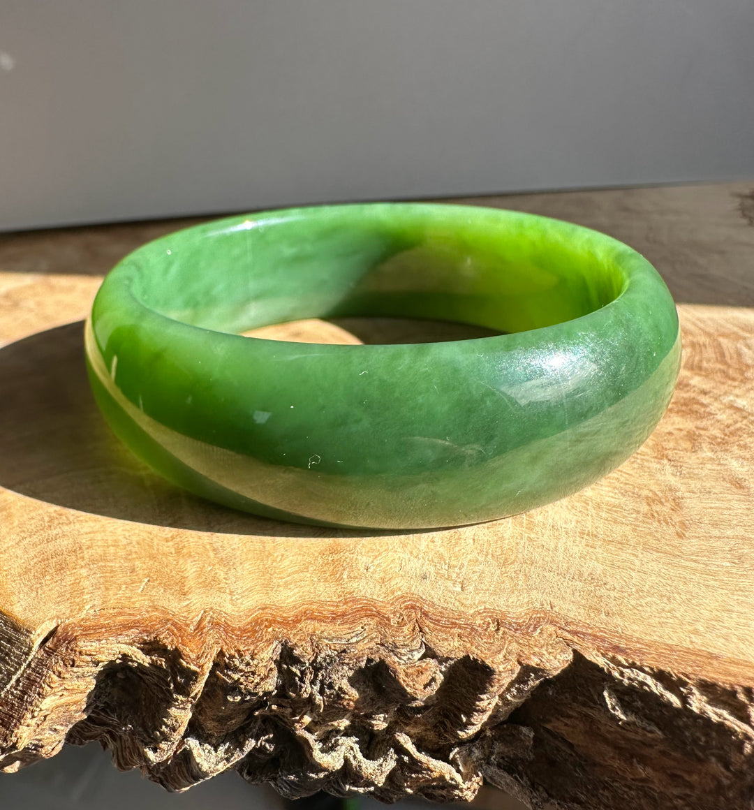 AA Grade Siberian Bangle 60 x 19mm in rich green jade close-up side view on wood surface