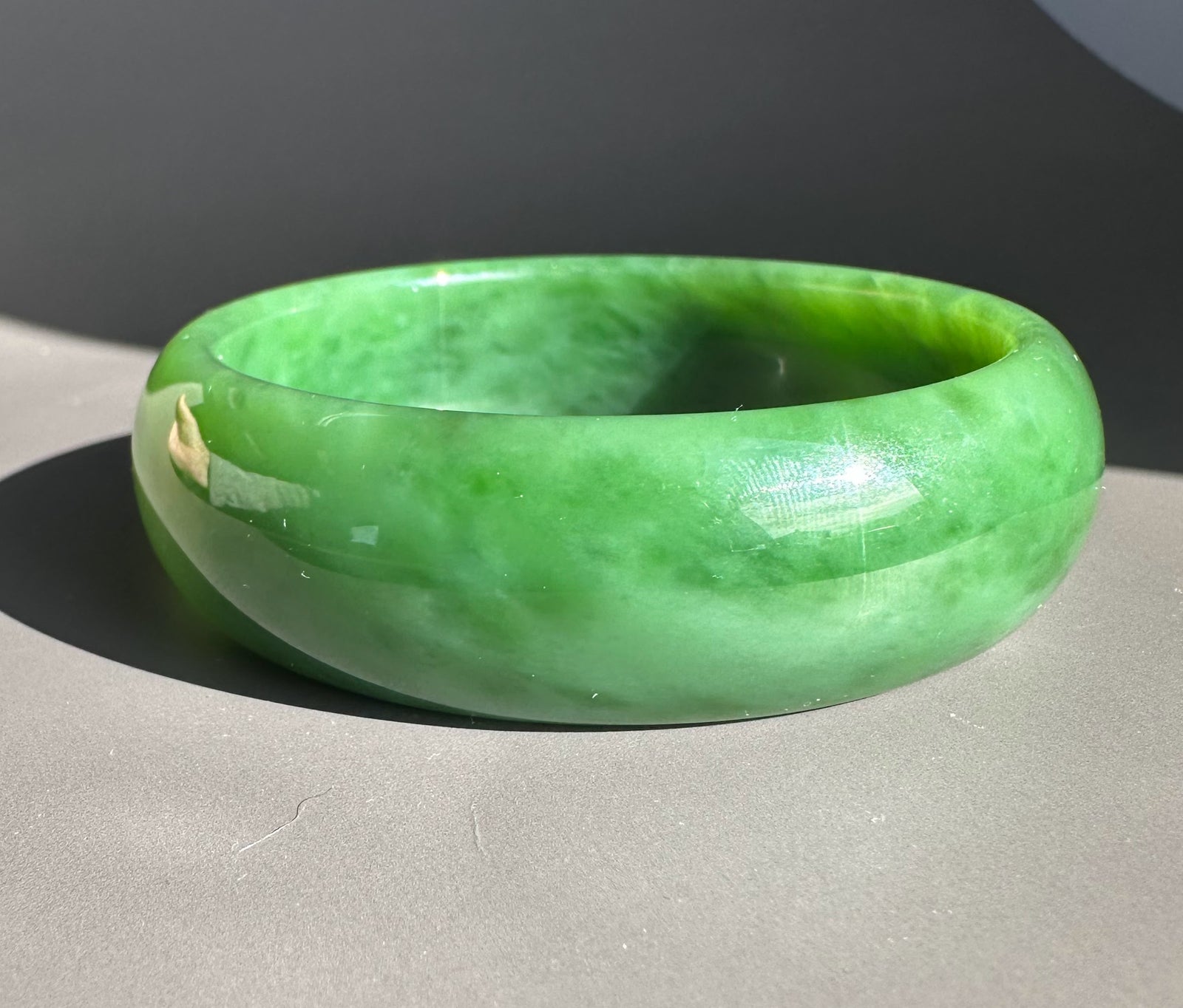 AA Grade Siberian Jade Bangle in bright green resting on a light surface
