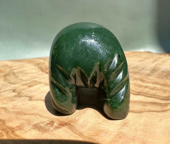 Green jade bear walking sculpture on a wooden surface