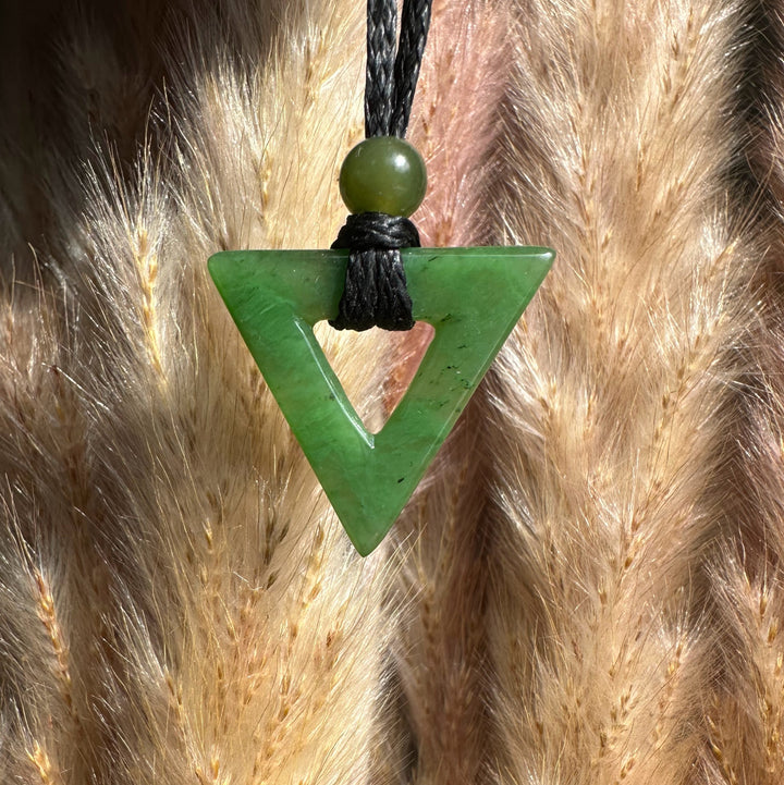 Green jade triangle pendant with hollow center on a black cord and bead